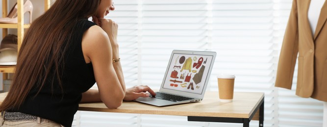 Photo of Professional stylist making collage with outfit on laptop at desk indoors