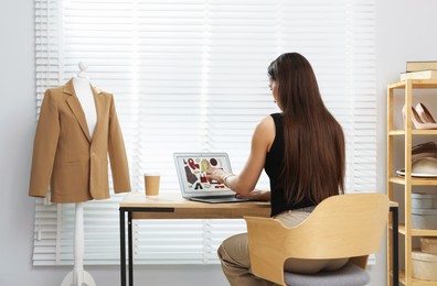 Photo of Professional stylist making collage with outfit on laptop at desk indoors