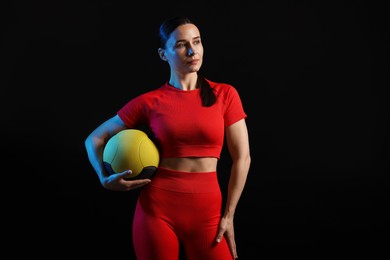 Photo of Woman with medicine ball on black background