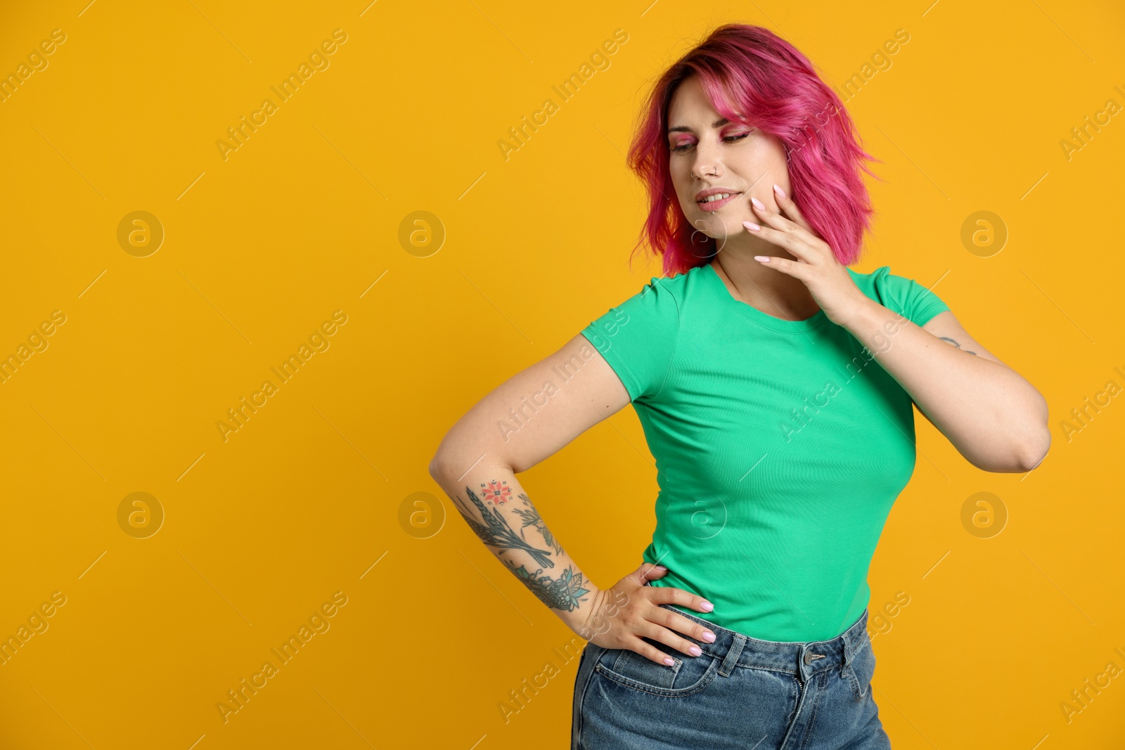Beautiful woman with pink dyed hair on yellow background, space for text Photo of Beautiful woman with pink dyed hair on yellow background, space for text