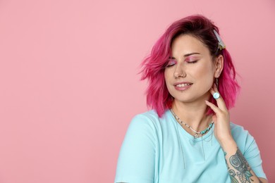 Photo of Beautiful woman with bright dyed hair on pink background, space for text