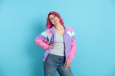 Photo of Beautiful woman with pink dyed hair on light blue background