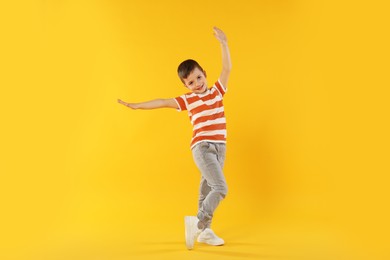 Photo of Happy little boy dancing on orange background