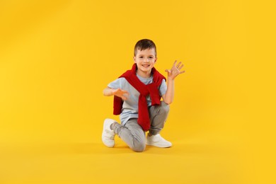 Photo of Happy little boy dancing on orange background