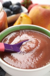 Photo of Baby food. Eating tasty puree with spoon at table, closeup