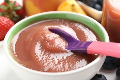 Photo of Baby food. Eating tasty puree with spoon at white table, closeup