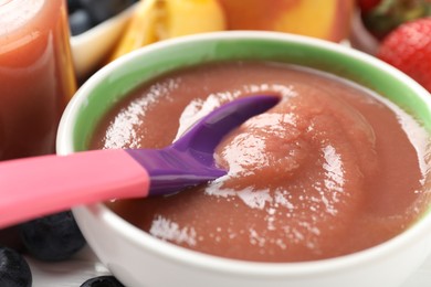 Photo of Baby food. Eating tasty puree with spoon at white table, closeup