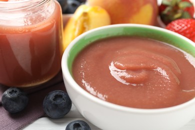 Photo of Baby food. Tasty puree in bowl and ingredients on white wooden table, closeup