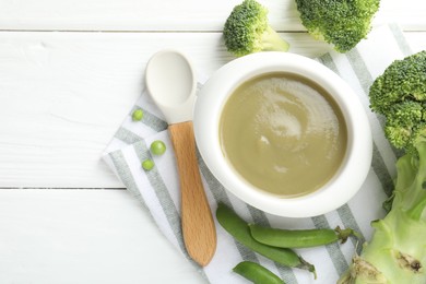Photo of Baby food. Tasty puree in bowl, spoon and ingredients on white wooden table, flat lay. Space for text