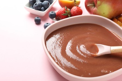 Photo of Baby food. Eating tasty puree with spoon at pink table, closeup. Space for text