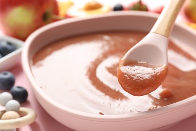 Photo of Baby food. Eating tasty puree with spoon at pink table, selective focus