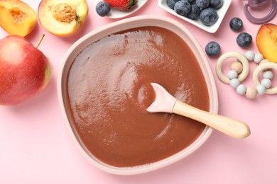 Photo of Baby food. Tasty puree in bowl, spoon, teether and ingredients on pink table, flat lay
