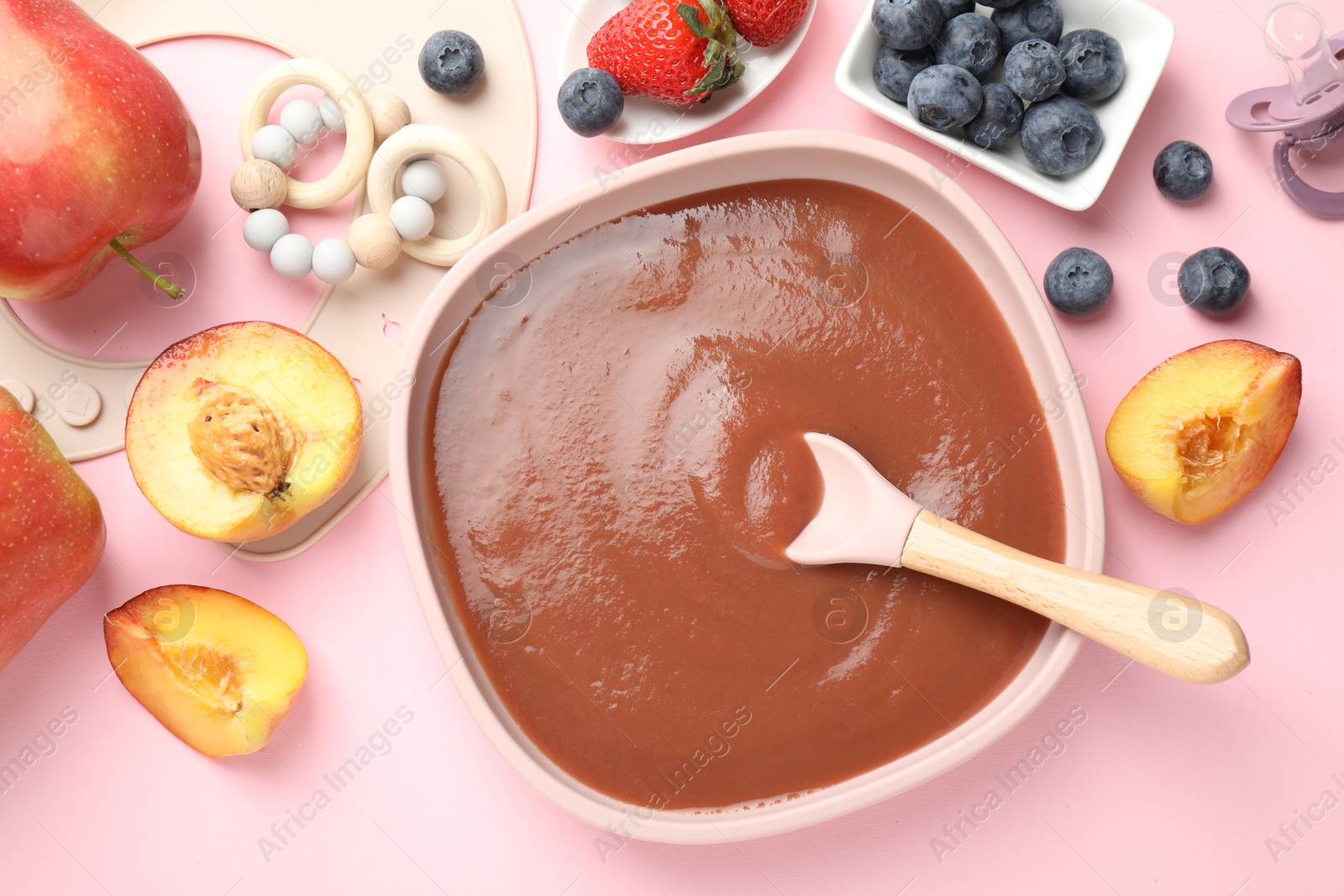 Baby food. Tasty puree in bowl, spoon, teether and ingredients on pink table, flat lay Photo of Baby food. Tasty puree in bowl, spoon, teether and ingredients on pink table, flat lay