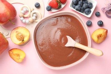 Photo of Baby food. Tasty puree in bowl, spoon, teether and ingredients on pink table, flat lay