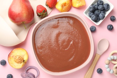 Photo of Baby food. Tasty puree in bowl, spoon and ingredients on pink table, flat lay