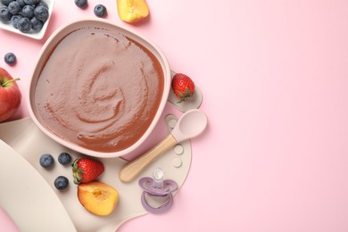 Photo of Baby food. Tasty puree in bowl, spoon and ingredients on pink table, flat lay. Space for text
