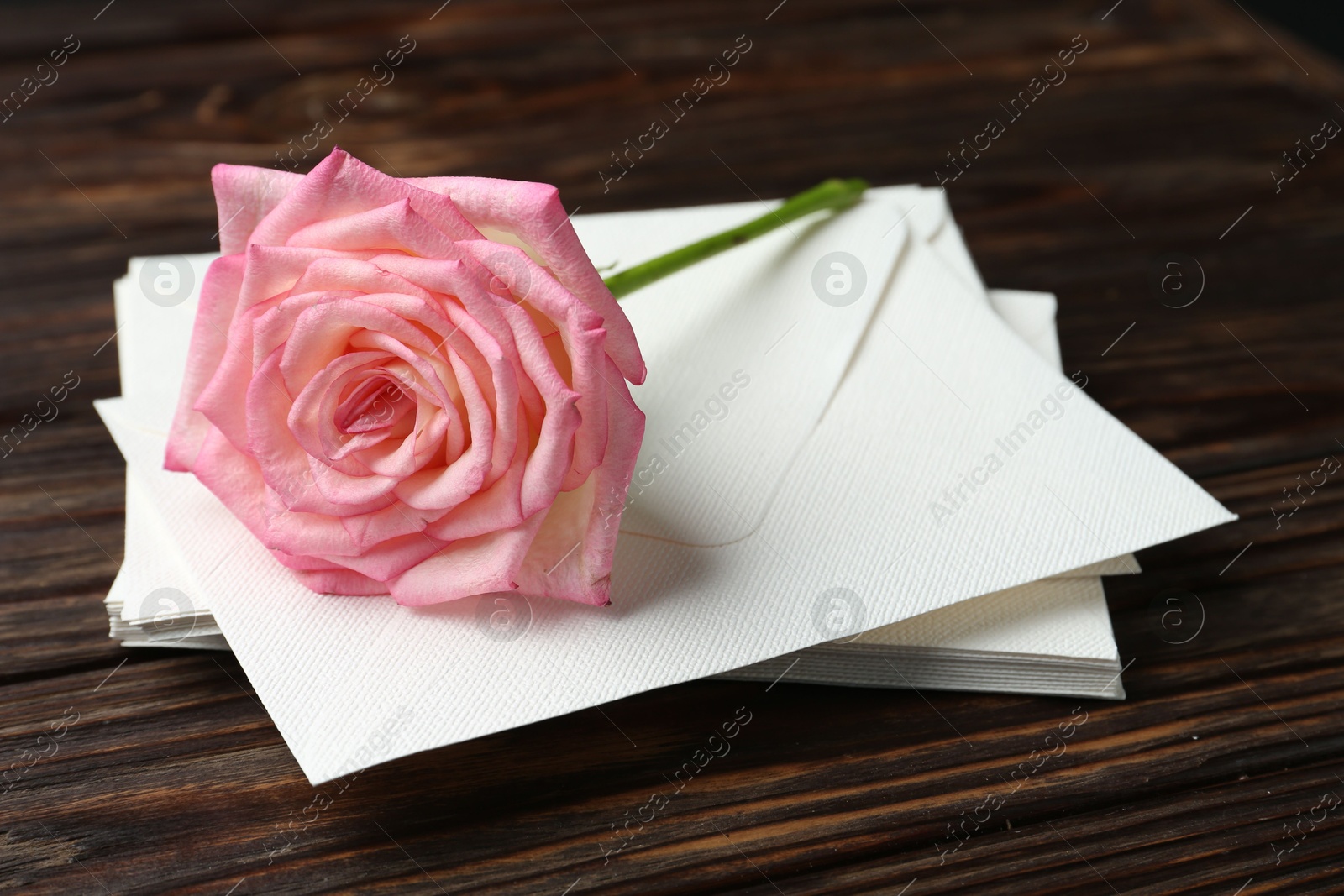 Stack of love letters and beautiful rose on wooden table, closeup Photo of Stack of love letters and beautiful rose on wooden table, closeup