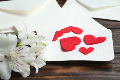 Photo of Many love letters, red hearts and beautiful lilies on wooden table, closeup
