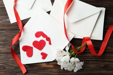 Photo of Many love letters, red hearts, ribbon and beautiful lilies on wooden table, flat lay