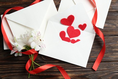 Photo of Many love letters, red hearts, ribbon and beautiful lilies on wooden table, flat lay