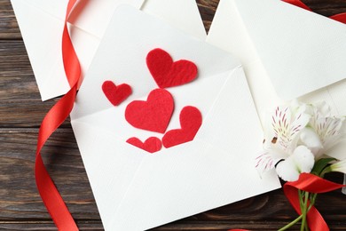 Photo of Many love letters, red hearts, ribbon and beautiful lilies on wooden table, flat lay