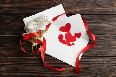 Photo of Love letters, red hearts, ribbon and beautiful lilies on wooden table, flat lay