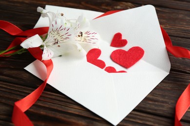 Photo of Love letters, red hearts, ribbon and beautiful lilies on wooden table, closeup
