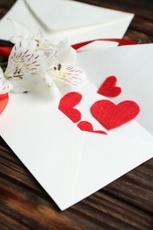 Photo of Love letters, red hearts and beautiful lilies on wooden table, closeup