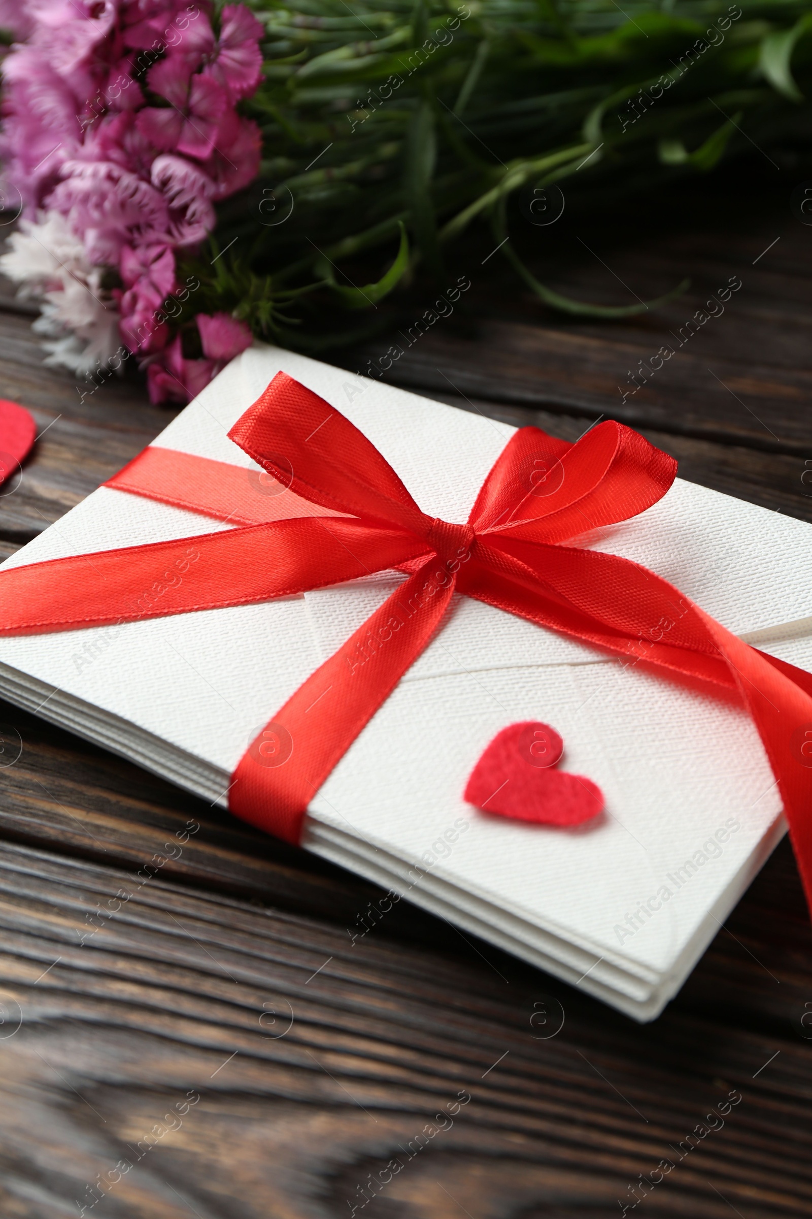 Stack of love letters, red hearts and beautiful flowers on wooden table, closeup Photo of Stack of love letters, red hearts and beautiful flowers on wooden table, closeup