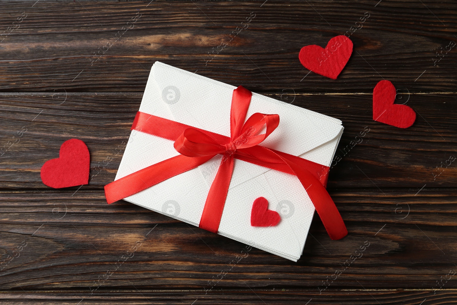 Stack of love letters and red hearts on wooden table, flat lay Photo of Stack of love letters and red hearts on wooden table, flat lay
