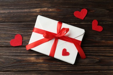 Photo of Stack of love letters and red hearts on wooden table, flat lay