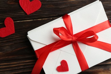 Photo of Stack of love letters and red hearts on wooden table, flat lay