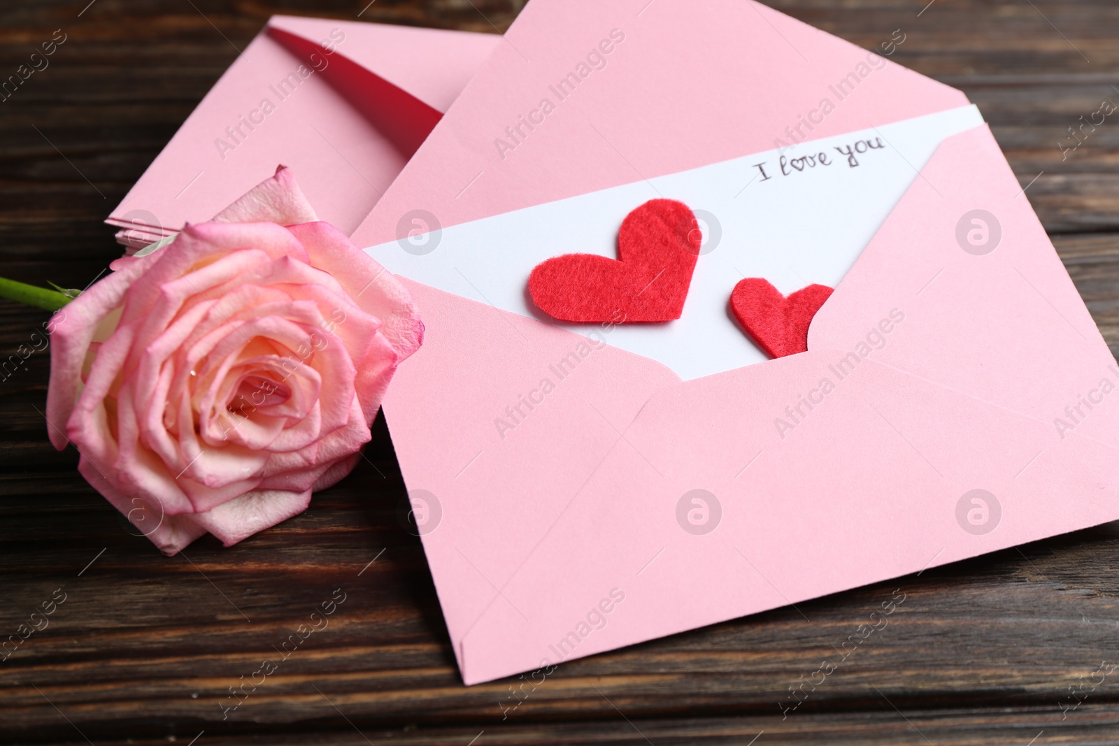 Love letter, envelopes, beautiful rose and red hearts on wooden table, closeup Photo of Love letter, envelopes, beautiful rose and red hearts on wooden table, closeup