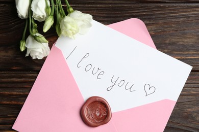 Photo of Letter with phrase I Love You, envelope and beautiful flowers on wooden table, flat lay