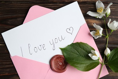 Photo of Letter with phrase I Love You, envelope and beautiful flowers on wooden table, flat lay