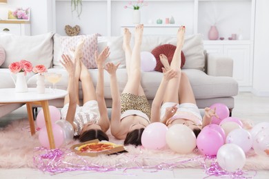 Photo of Friends spending time together on floor near sofa at home