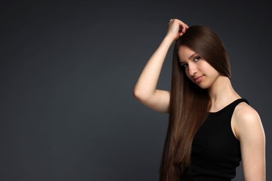 Photo of Portrait of beautiful teenage girl with healthy long hair on dark grey background. Space for text