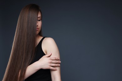Photo of Teenage girl with healthy long hair on dark grey background. Space for text