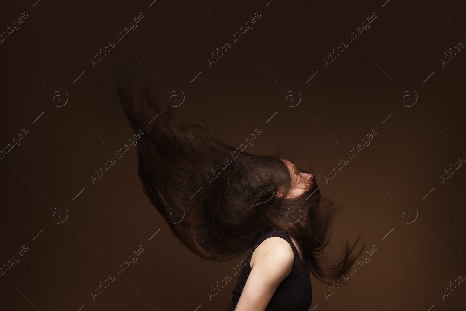 Teenage girl with healthy long hair on brown background Photo of Teenage girl with healthy long hair on brown background
