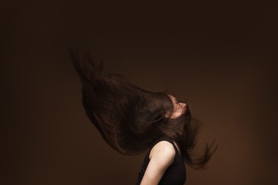 Photo of Teenage girl with healthy long hair on brown background