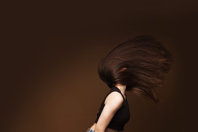 Photo of Teenage girl with healthy long hair on brown background. Space for text