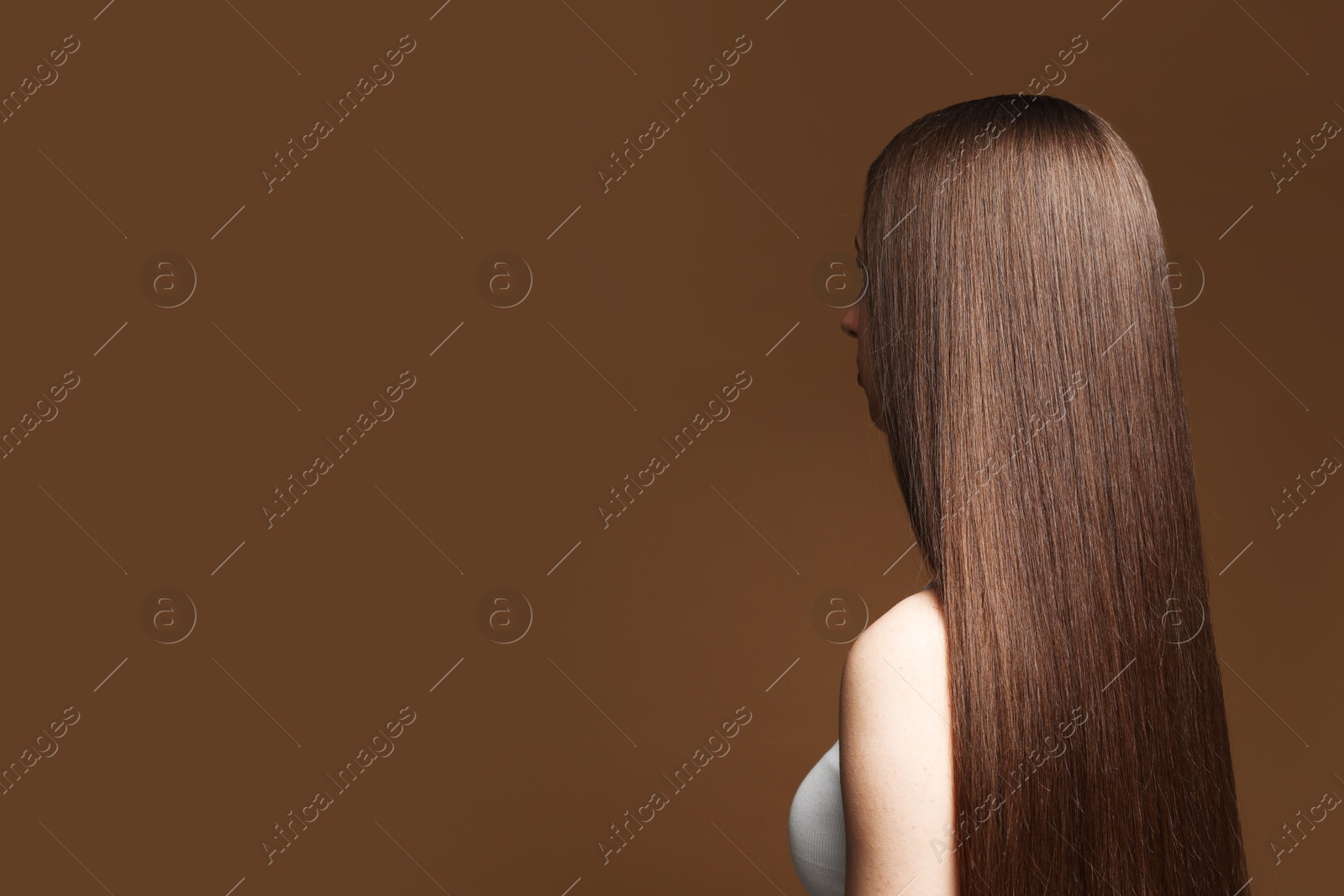 Photo of Teenage girl with healthy long hair on brown background. Space for text