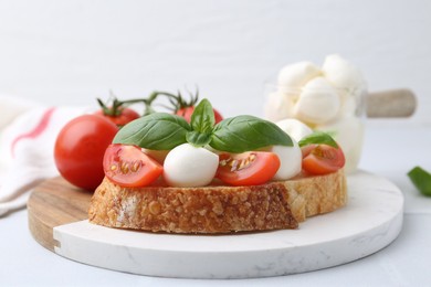Photo of Tasty sandwich with mozzarella cheese, tomatoes and basil on light table, closeup