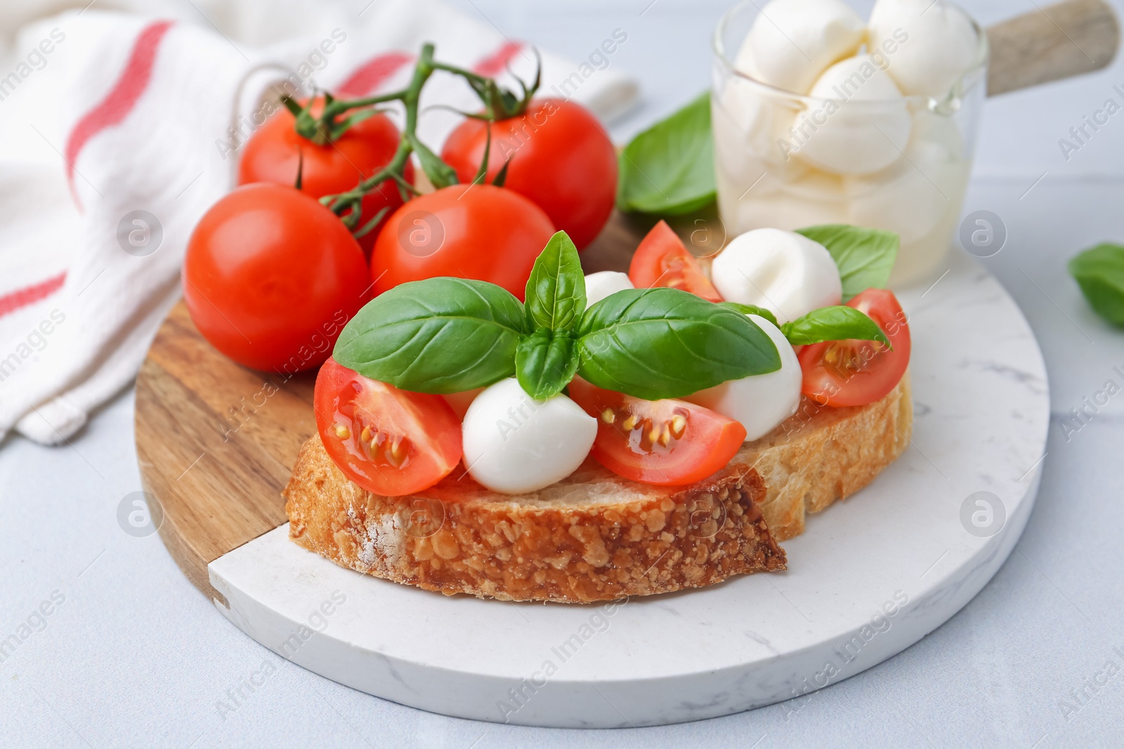 Tasty sandwich with mozzarella cheese, tomatoes and basil on light grey textured table, closeup Photo of Tasty sandwich with mozzarella cheese, tomatoes and basil on light grey textured table, closeup