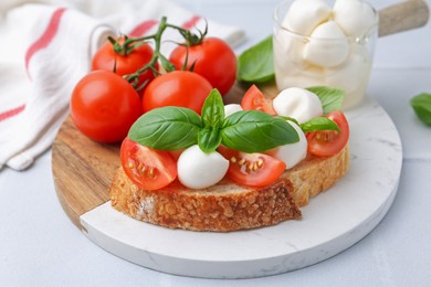 Photo of Tasty sandwich with mozzarella cheese, tomatoes and basil on light grey textured table, closeup