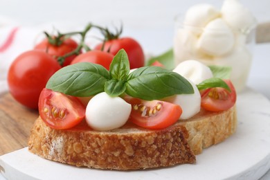 Photo of Tasty sandwich with mozzarella cheese, tomatoes and basil on table, closeup
