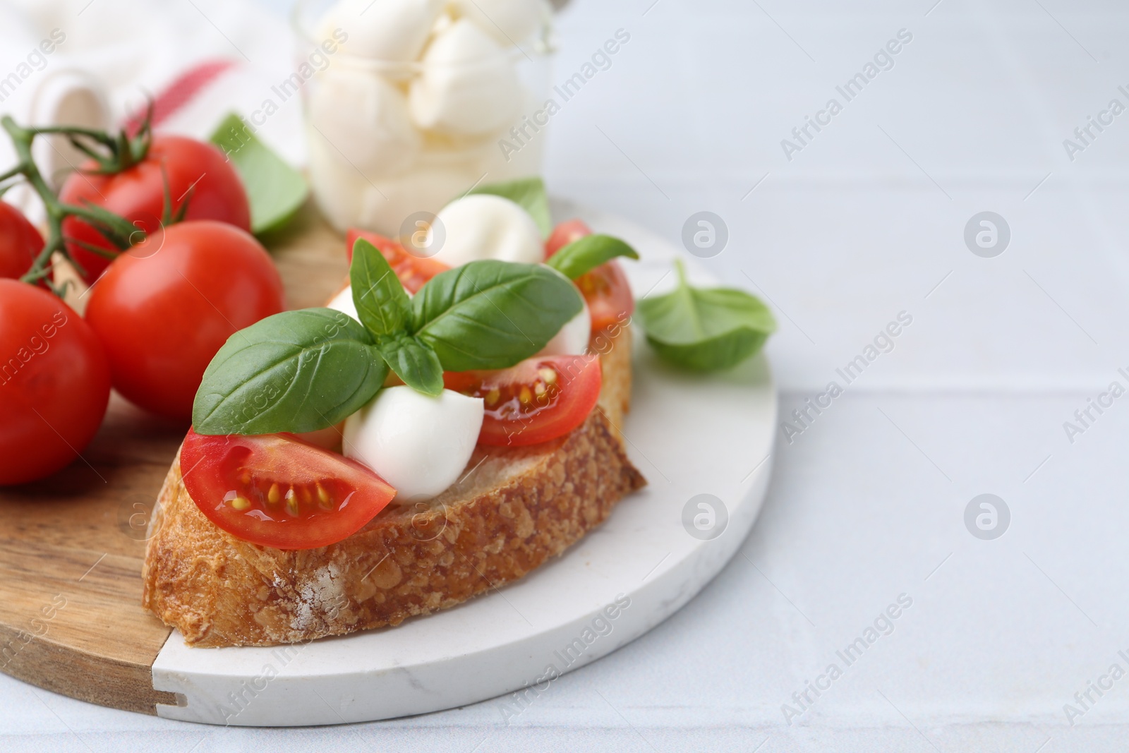 Tasty sandwich with mozzarella cheese, tomatoes and basil on light tiled table, closeup. Space for text Photo of Tasty sandwich with mozzarella cheese, tomatoes and basil on light tiled table, closeup. Space for text