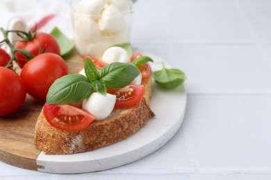 Photo of Tasty sandwich with mozzarella cheese, tomatoes and basil on light tiled table, closeup. Space for text