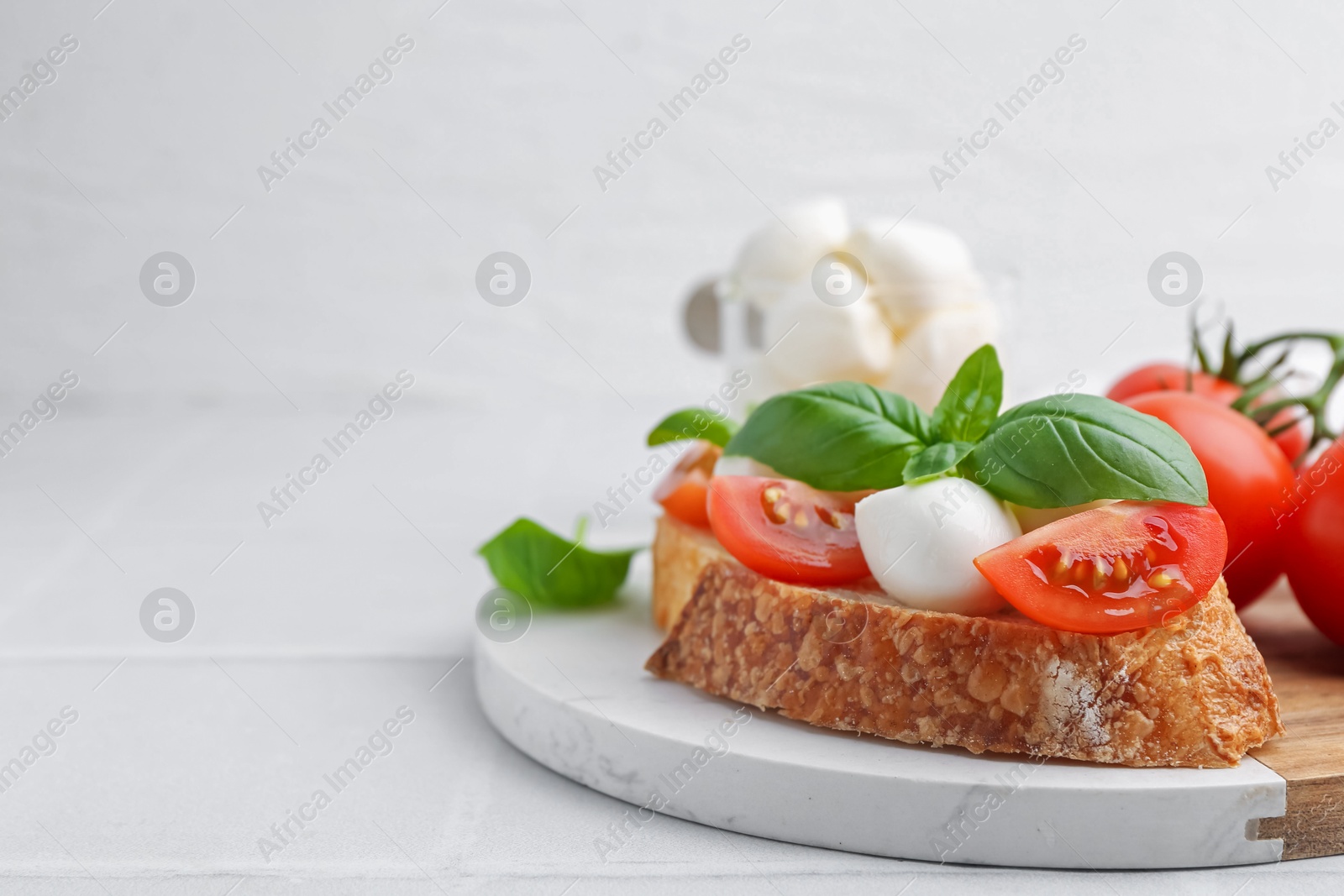 Tasty sandwich with mozzarella cheese, tomatoes and basil on light tiled table, closeup. Space for text Photo of Tasty sandwich with mozzarella cheese, tomatoes and basil on light tiled table, closeup. Space for text