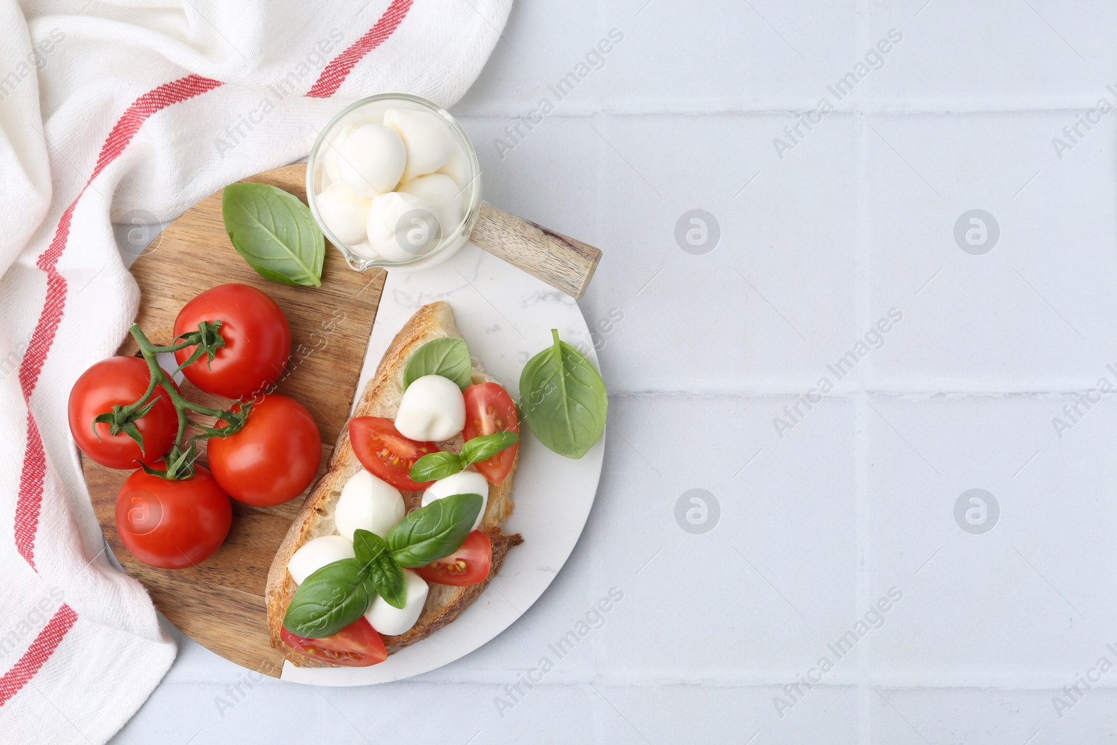 Tasty sandwich with mozzarella cheese, tomatoes and basil on light tiled table, top view. Space for text Photo of Tasty sandwich with mozzarella cheese, tomatoes and basil on light tiled table, top view. Space for text
